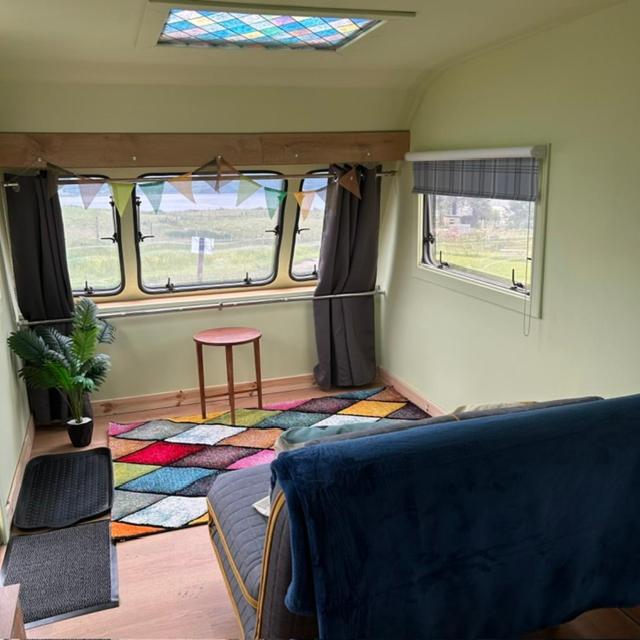 a room with a couch and a table and windows at the buttercup shed in Lochcarron