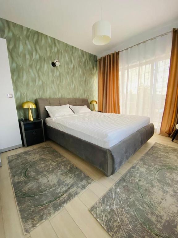 a bedroom with a large bed and two rugs at Debres Apartment Aiud in Aiud