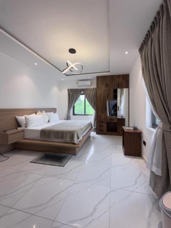 a large bedroom with a bed and a television at Executive Cozy Suite at THE HIDDEN DOMUS I Wenchi Suite in Accra