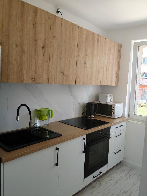 Eine Küche mit weißen Schränken, Spüle und Mikrowelle in der Unterkunft APT w centrum in Suwałki