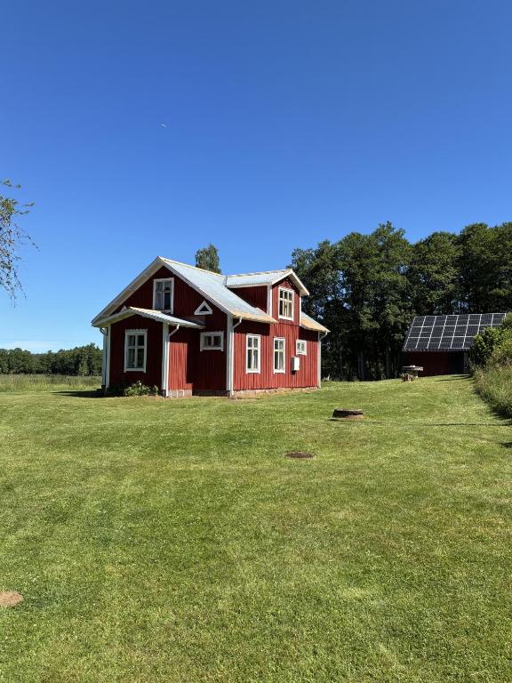 a red house in a field with solar panels at Örnafälla in Örnafälla