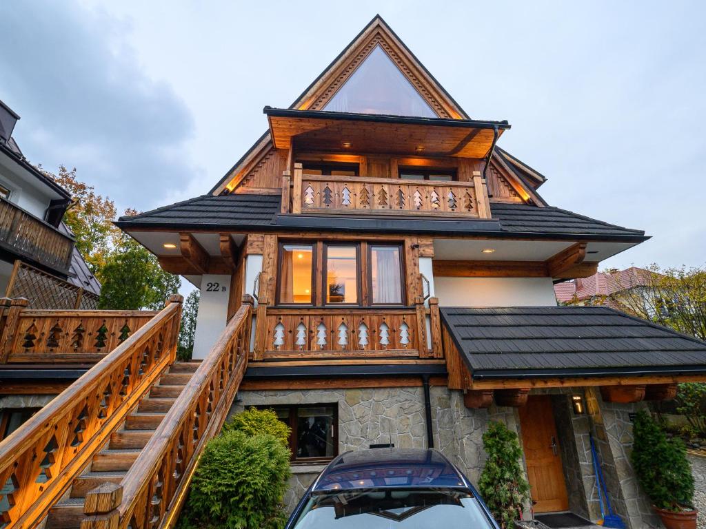 a house with a balcony and a car parked in front at VisitZakopane - Willa Bajka Apartments in Zakopane