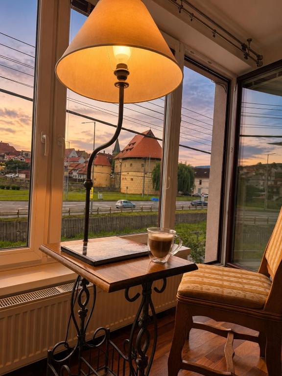 a lamp sitting on a table in front of a window at Contact Apartman in Bardejov