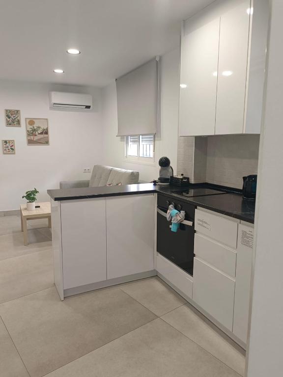 a kitchen with white cabinets and black counter tops at Edificio Mañez - Bajo in La Línea de la Concepción