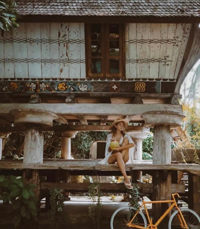 a girl sitting on a porch of a house with a bike at Resort JUNGLEROOM Canggu in Canggu