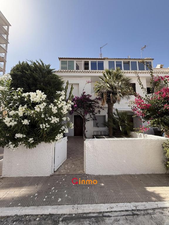 a white building with trees and flowers in front of it at Chalet en Mar Menor Urb las Góndolas in La Manga del Mar Menor
