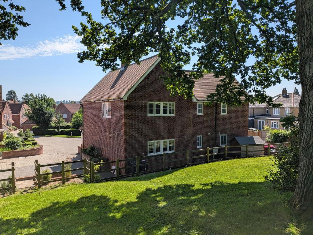 a brick house with a fence in front of a yard at Wyndham Court - Midhurst in Midhurst