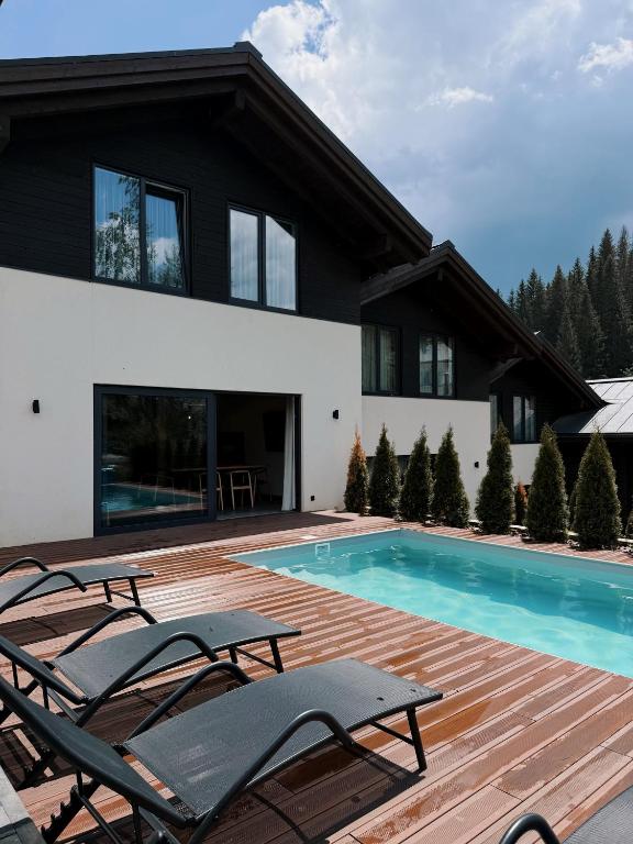 a house with a swimming pool and chairs at Альпійські шале Душа in Palyanytsya
