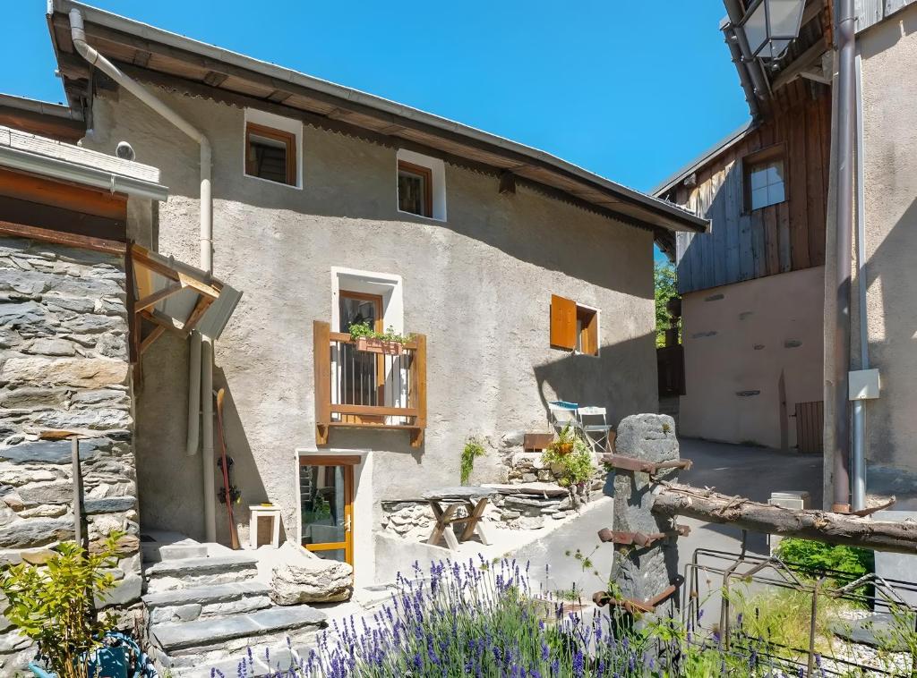 a stone house with a balcony and purple flowers at Chalet Le Hameau Tranquille in Courchevel