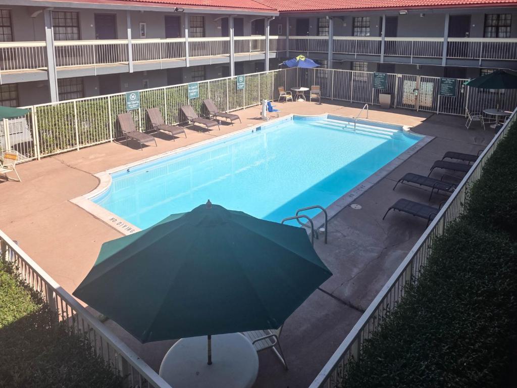 a large swimming pool with an umbrella and chairs at Motel 6 Aurora, CO - Medical Center in Aurora