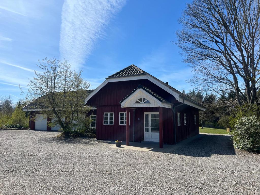 a red barn with a white door in a driveway at Mosborg Gæstehus in Ulfborg