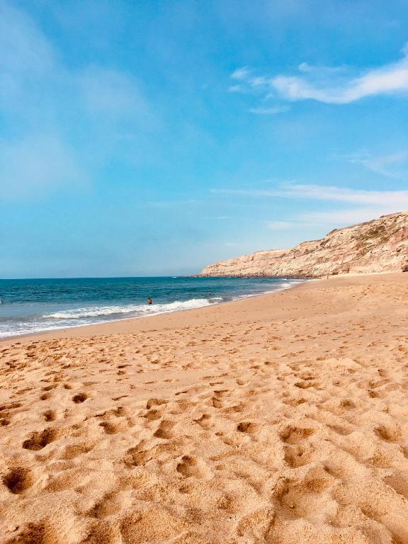 a beach with footprints in the sand and the ocean at Vilamar - Ribamar in Ribamar