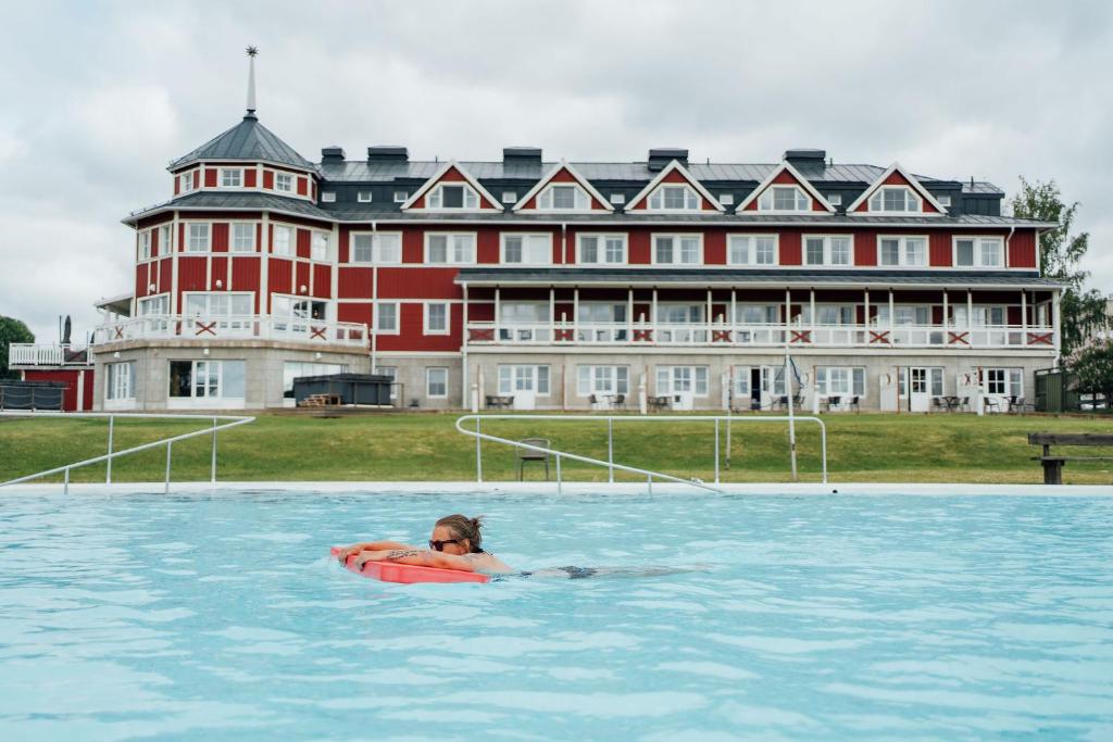 a woman in a pool in front of a large building at Grand Arctic Resort in Överkalix