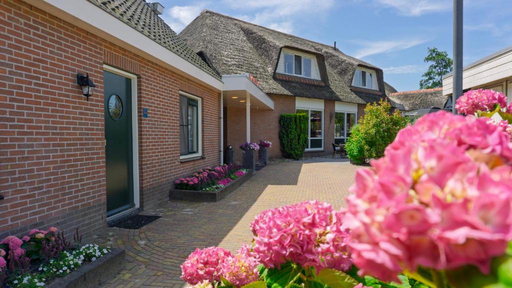 a brick house with pink flowers in front of it at Hotel de Harmonie in Giethoorn