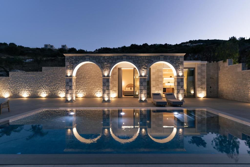 a villa with a swimming pool at night at Alýria Sea Side Suites in Agios Nikolaos