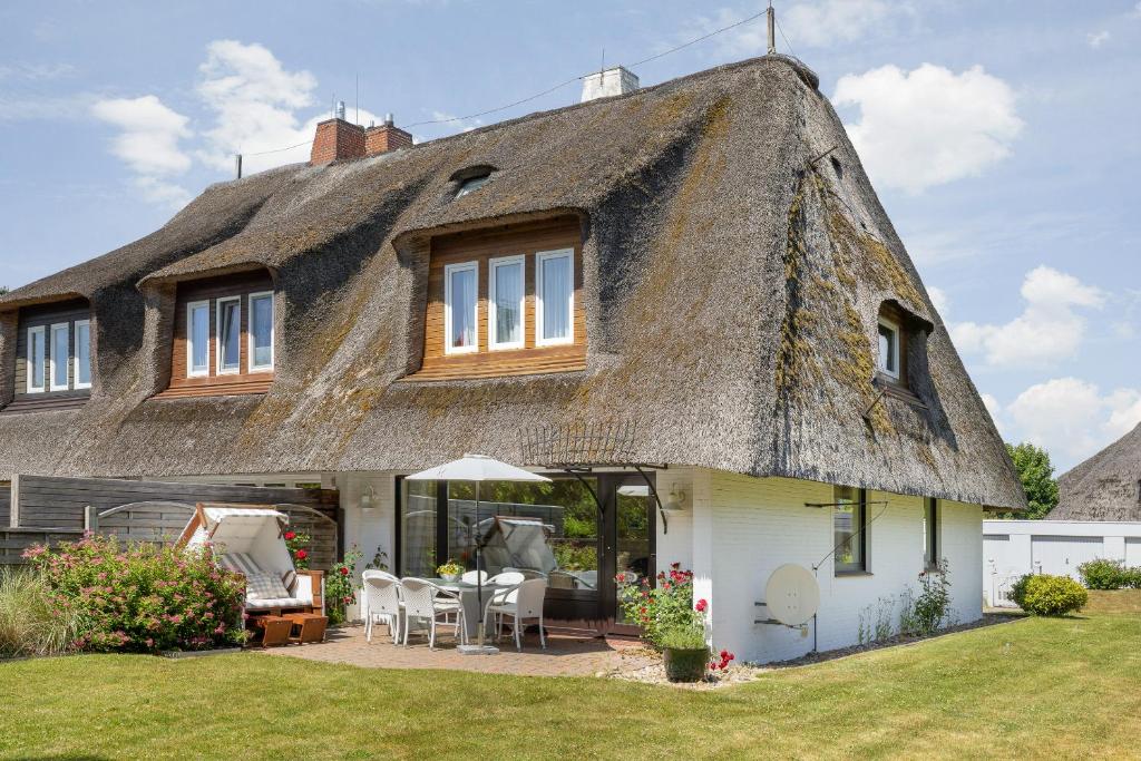 a thatch roofed house with a patio at Henning in Keitum