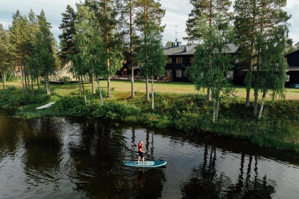 a person is standing on a paddle board in the water at Arctic River Lodge in Tärendö