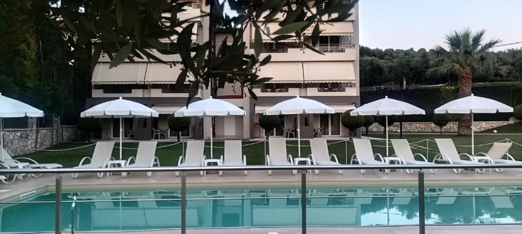 a pool with chairs and umbrellas next to a building at Alex House in Zacharo