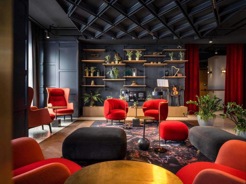a waiting room with red chairs and tables at Hotel Am Konzerthaus - MGallery Collection in Vienna