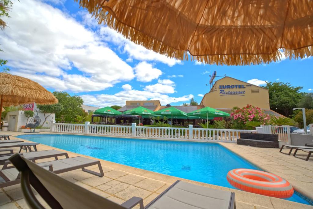 a pool at a resort with chairs and umbrellas at Eurotel Parc Expo Airport Montpellier in Pérols