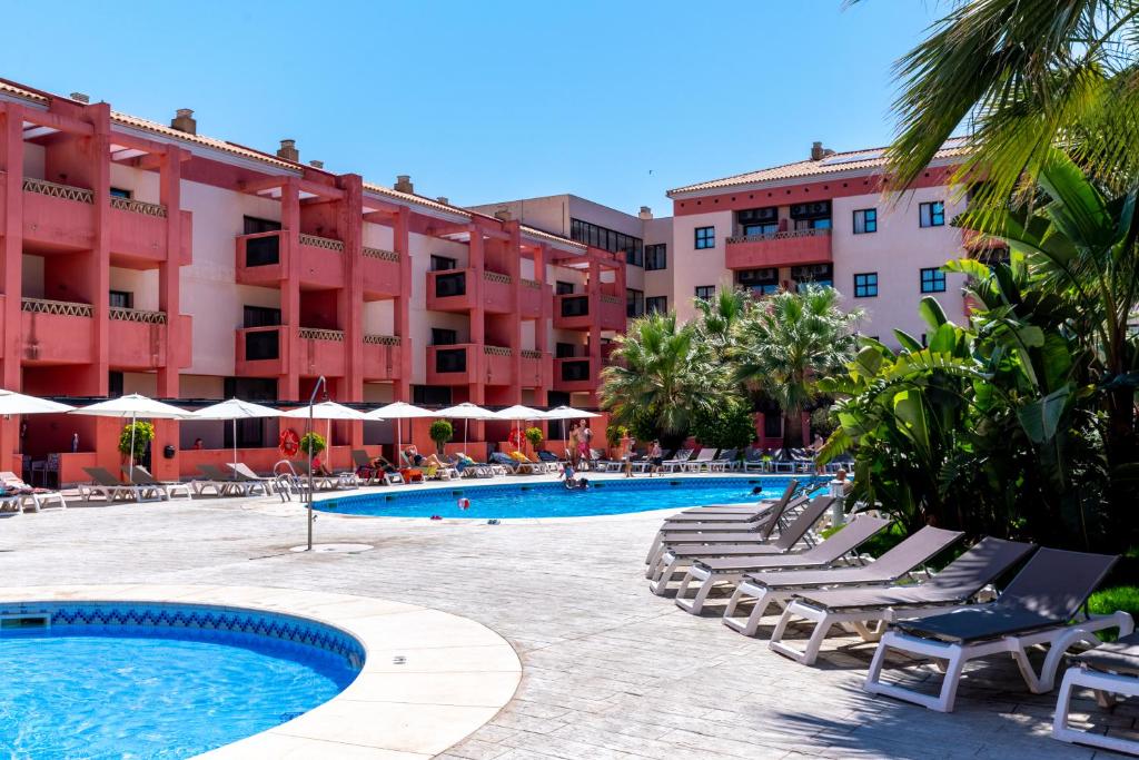 a resort with a swimming pool and chairs and buildings at Leo Punta Umbría in Punta Umbría