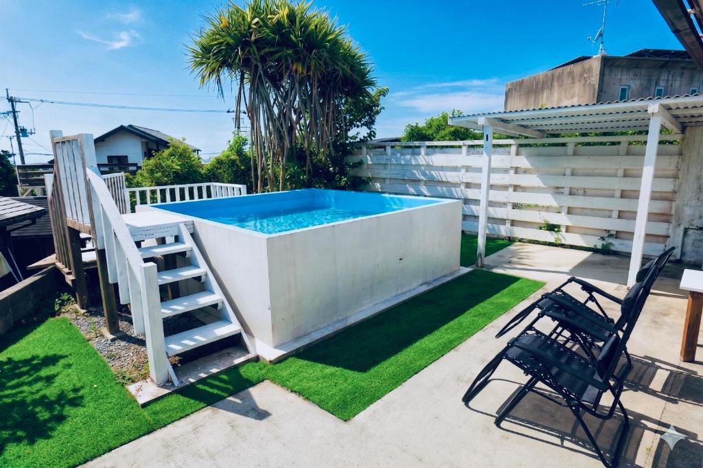 a swimming pool in a yard with a ladder and chairs at MOTOBU Ocean Private Villa in Motobu