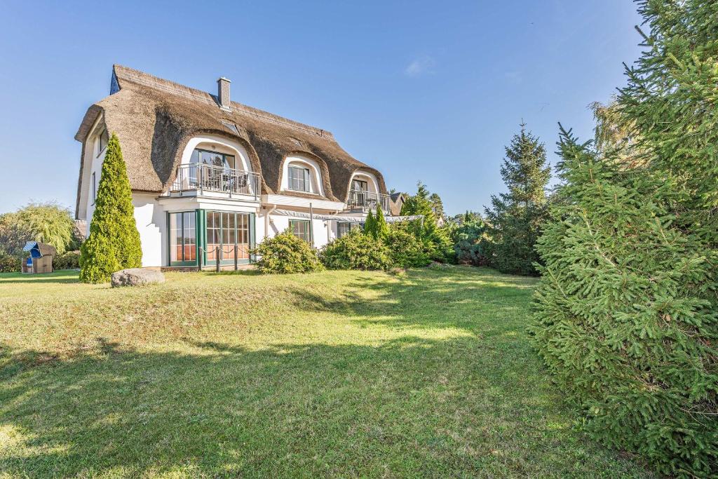 an old house with a thatched roof on a yard at Ostseeglück App Mittagsonne in Loddin