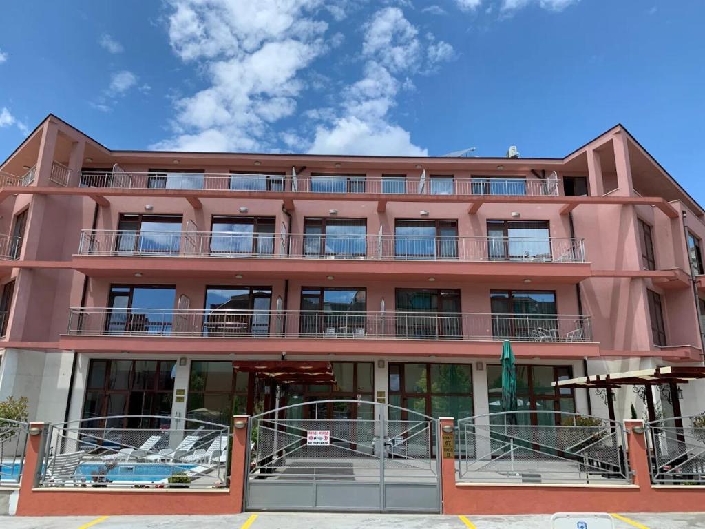 a red building with balconies on the side of it at Cattleya in Nesebar