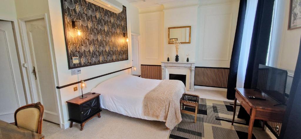 a bedroom with a bed and a desk and a fireplace at Suite Millésime du Château - Proche Océan in Gaillan-en-Médoc