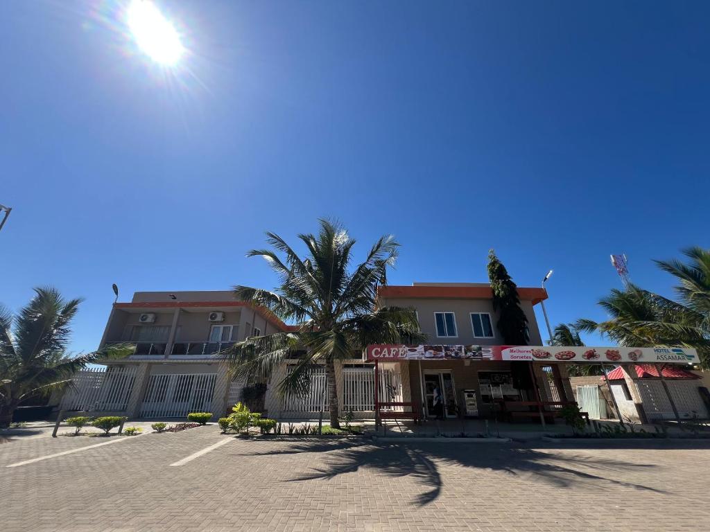 a building on a street with palm trees and the sun at Hotel Residencial Assamar in Pemba