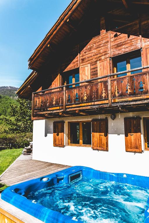 a house with a hot tub on a deck at Chalet Le Serre des Oiseaux in Saint-Chaffrey