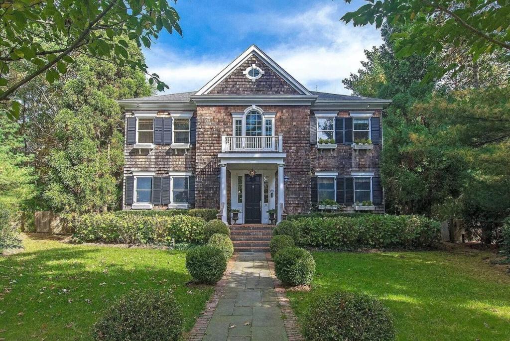 a brick house with a porch and a lawn at Villa Grand Horizon in East Hampton