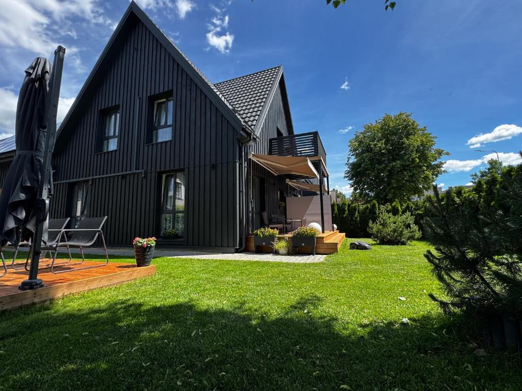 a black house with a yard with green grass at G17-1 Palanga in Palanga