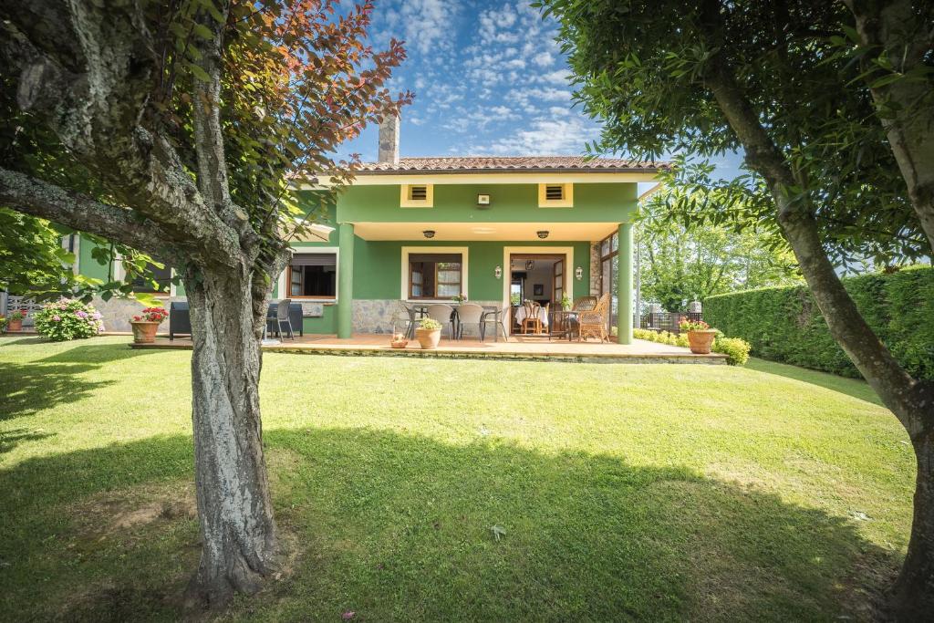 a green house with a lawn in front of it at Casa Rural El FerJo in Colunga