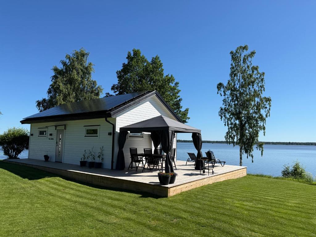 a gazebo with chairs and tables on a deck next to the water at Villa Guldkusten in Kolsva