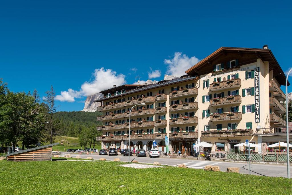 a hotel in the mountains with a road in front of it at Hotel Villa Argentina in Cortina dʼAmpezzo