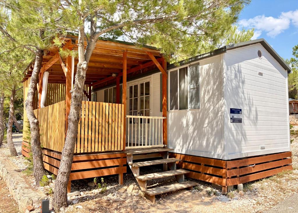 a tiny house with a staircase and a tree at Mobilehome Adams Glamping - Camp Adriatic in Primošten