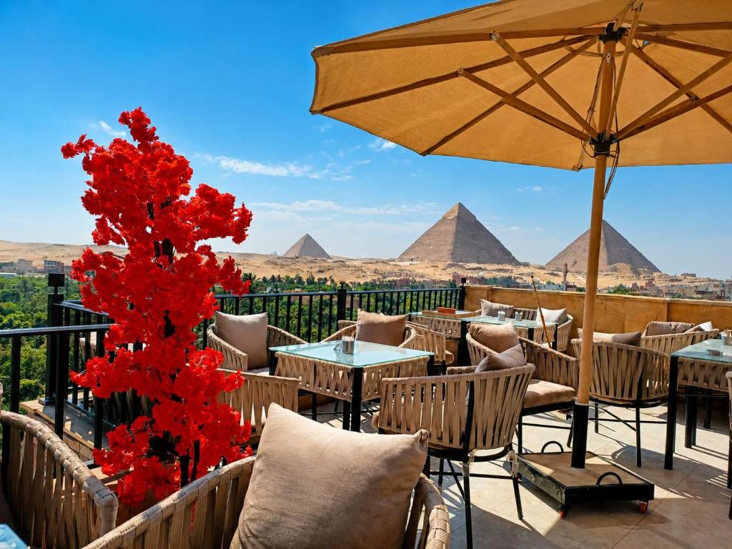 a patio with tables and an umbrella and pyramids at New Gardenia Pyramids - Rooftop in Cairo