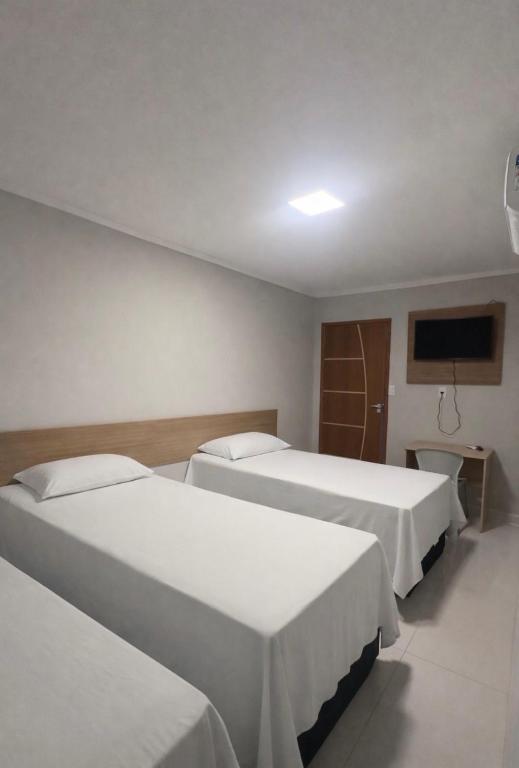 a hotel room with two beds and a flat screen tv at Chimarrão Hotel in Juazeiro