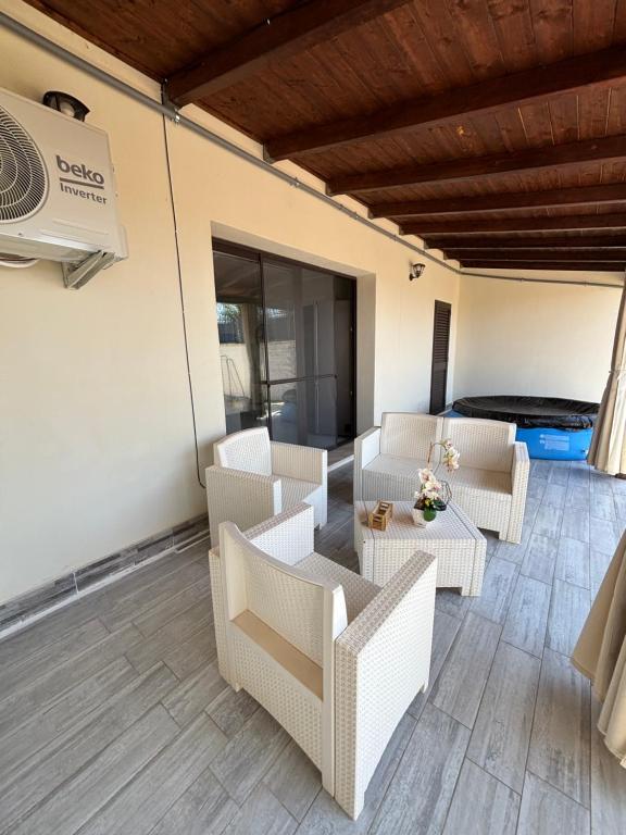 eine Terrasse mit weißen Stühlen und einem Tisch in der Unterkunft Villa ManuCamp in Reggio di Calabria