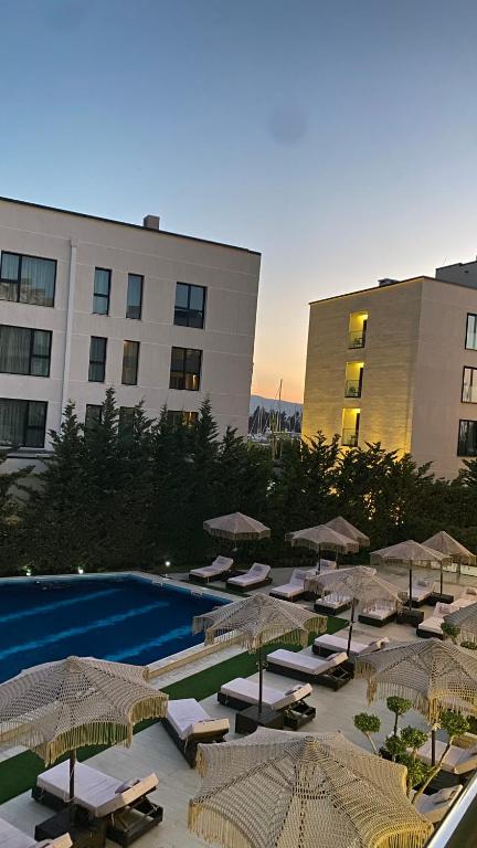 a pool with lounge chairs and umbrellas next to a building at Duki's Apartments in Orikum
