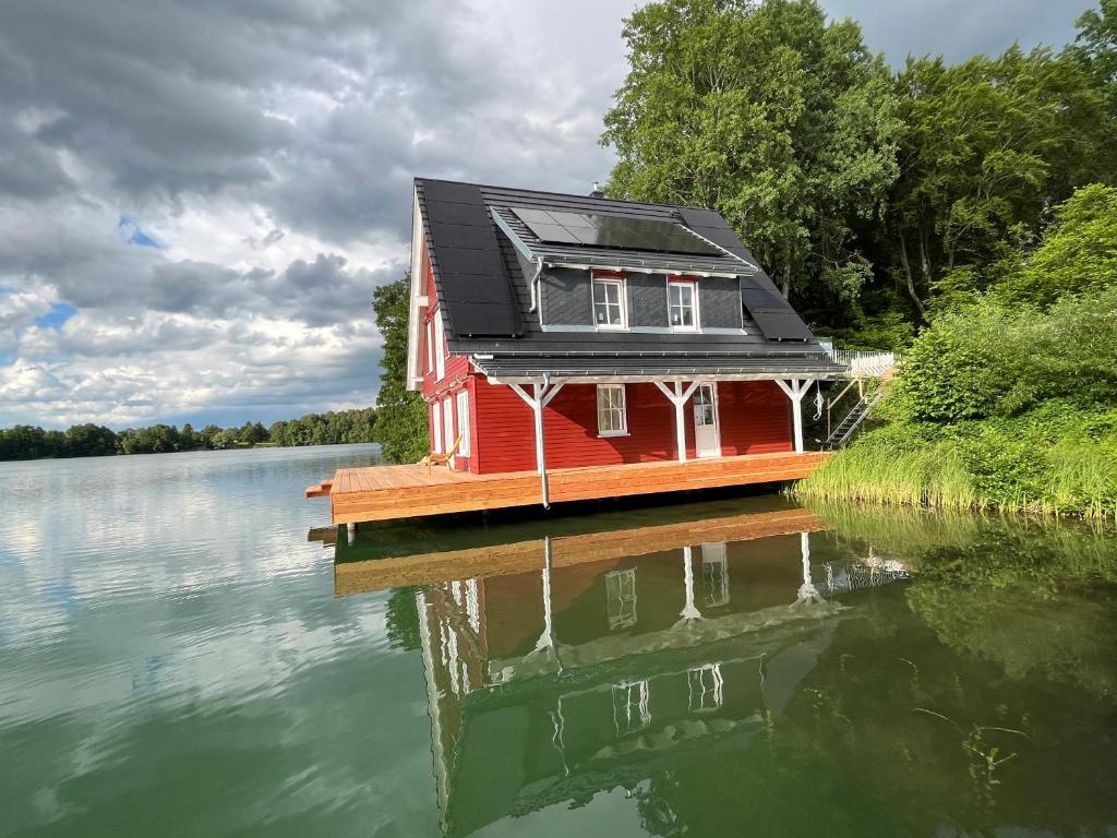 a small red house on a dock on a lake at Seehaeuser am Lindenhof in Lychen
