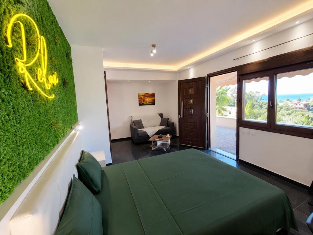 a room with a green wall with a bed and a couch at THEASIS 4 luxury studio with sea view in Neos Marmaras