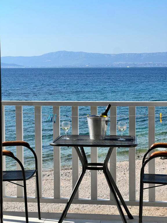 a table with a bottle of wine and two glasses on the beach at Apartments Vujic in Mirce