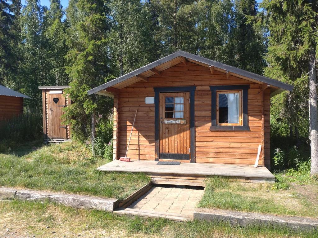 a wooden cabin with a door in the grass at JVT Cabins in Kiruna