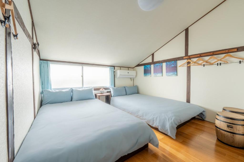 two beds in a room with white walls and wood floors at Atlantis Tengachaya - Whole house rental in Osaka