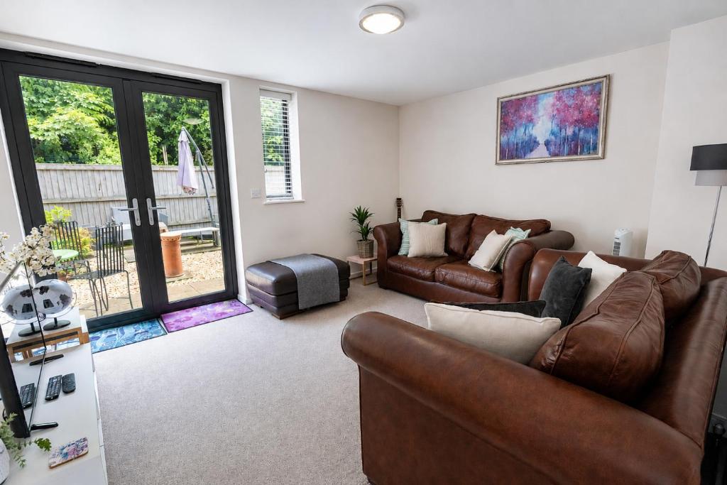 a living room with leather furniture and a sliding glass door at COTTON HOUSE - Peak District Escape, Walks, Canal & Cromford Mill in Matlock