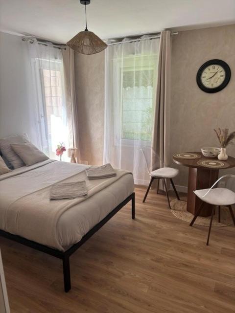 a bedroom with a bed and a table and a clock at Appartement proche Université Arras, parking gratuit et privé in Arras