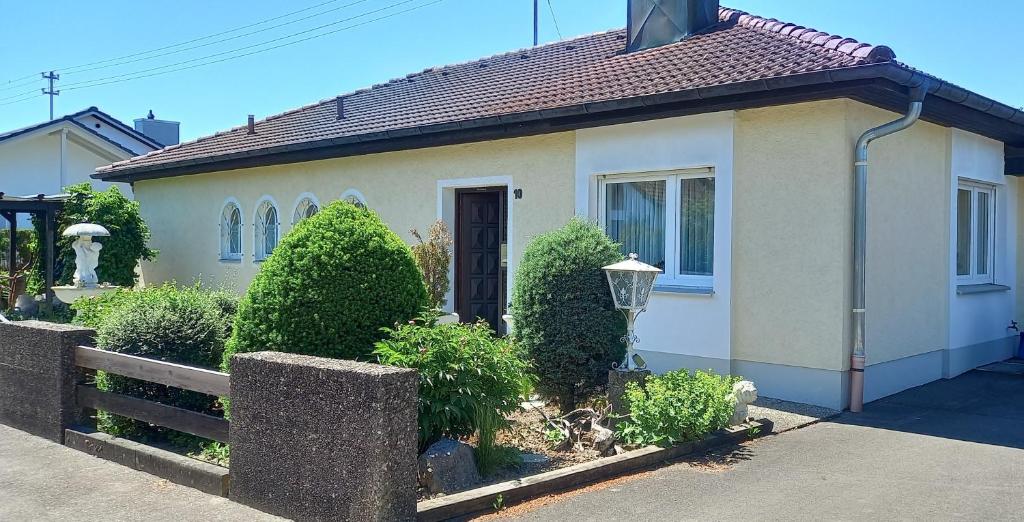 a small white house with a fence and bushes at Bungalow Au in Illertissen