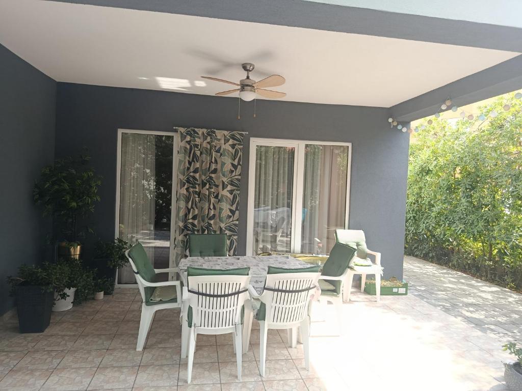 a patio with a table and chairs and a ceiling fan at Guest house Gloria in Šilo